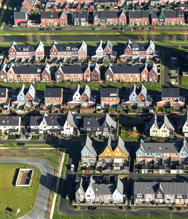 Een nieuwbouwwijk met kleurrijke huizen en veel groen met water.